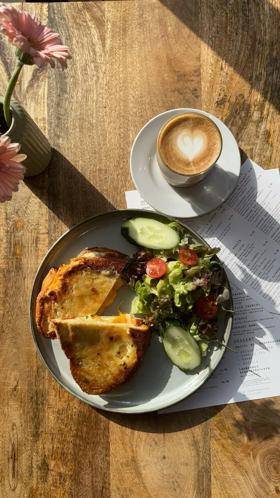 Frühstück mit Cappuccino und frischen Blumen in der Sonne